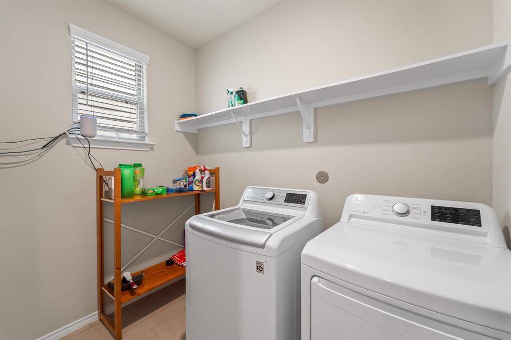 Spacious first-floor laundry room located just behind the kitchen and across from the garage—complete with shelving and natural light.