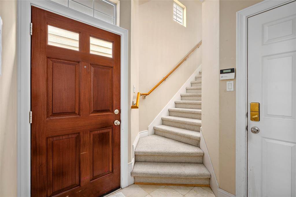 Upon entry, you're greeted by a clean, tiled foyer with direct access to the attached garage and a carpeted staircase leading to the main living areas. Natural light filters in from a high window, giving the space a warm and welcoming feel.