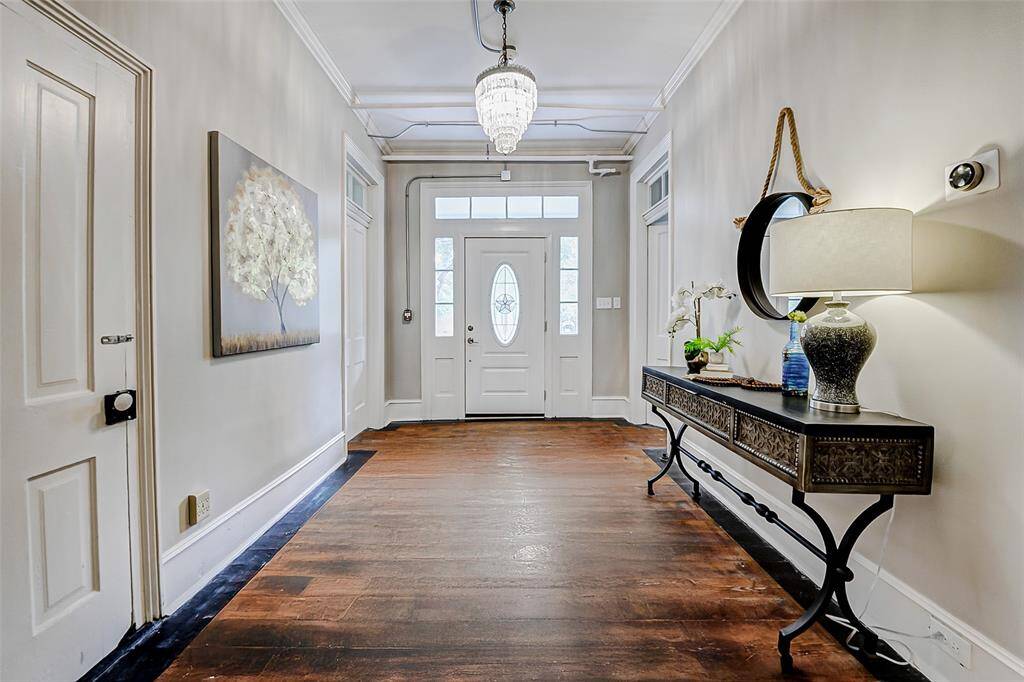 Welcome to the foyer, where the timeless beauty of what are believed to be original wood floors, fresh paint, crown molding, and 8" baseboards greet you. These classic elements reflect the home's rich history and craftsmanship.