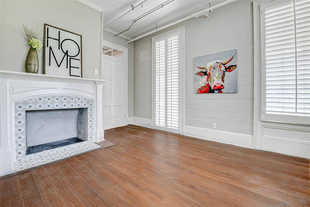 This spacious 10x18 room features a restored fireplace, shiplap walls, and plantation shutters, blending original charm with modern updates.