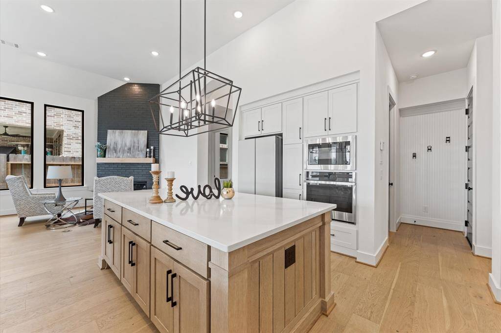 A modern elegant chandelier hangs above the island, adding a touch of sophistication.