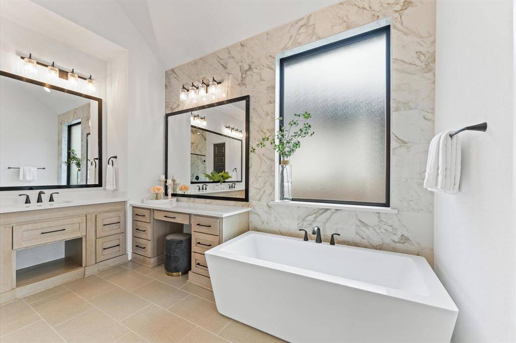 A deep soaking tub, positioned by a window, creates the perfect spot for unwinding.High-end fixtures and finishes elevate the space, making it feel like a spa at home.