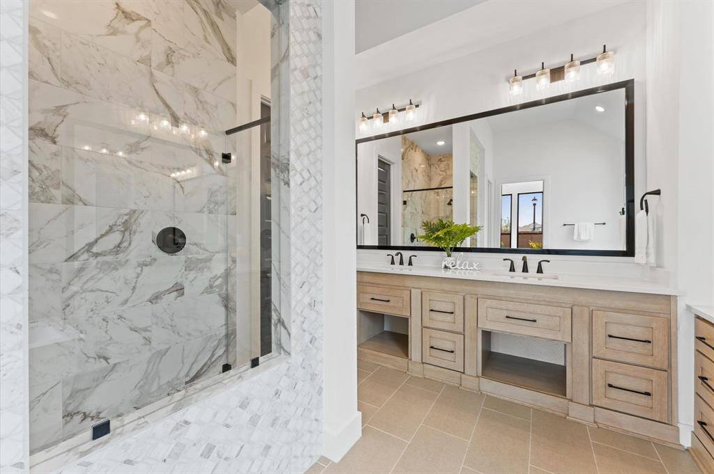 The spacious layout features dual vanities, offering plenty of room for two and a separate glass-enclosed shower offers a refreshing escape with modern finishes.