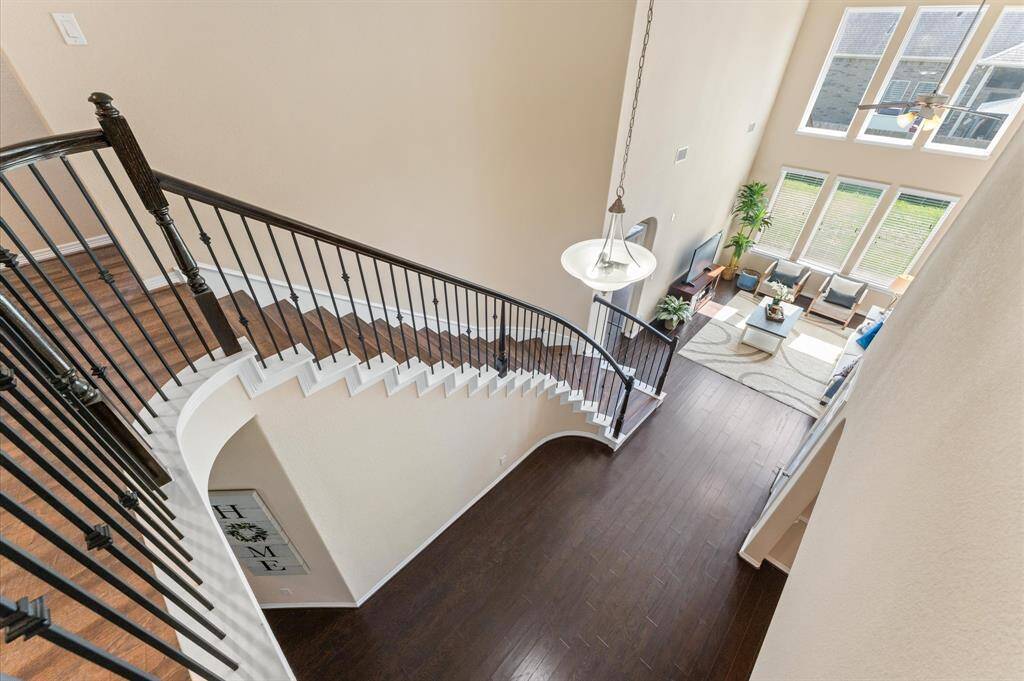 Just a few steps further, the view opens to the spacious living room below, with its soaring ceiling and bright natural light.