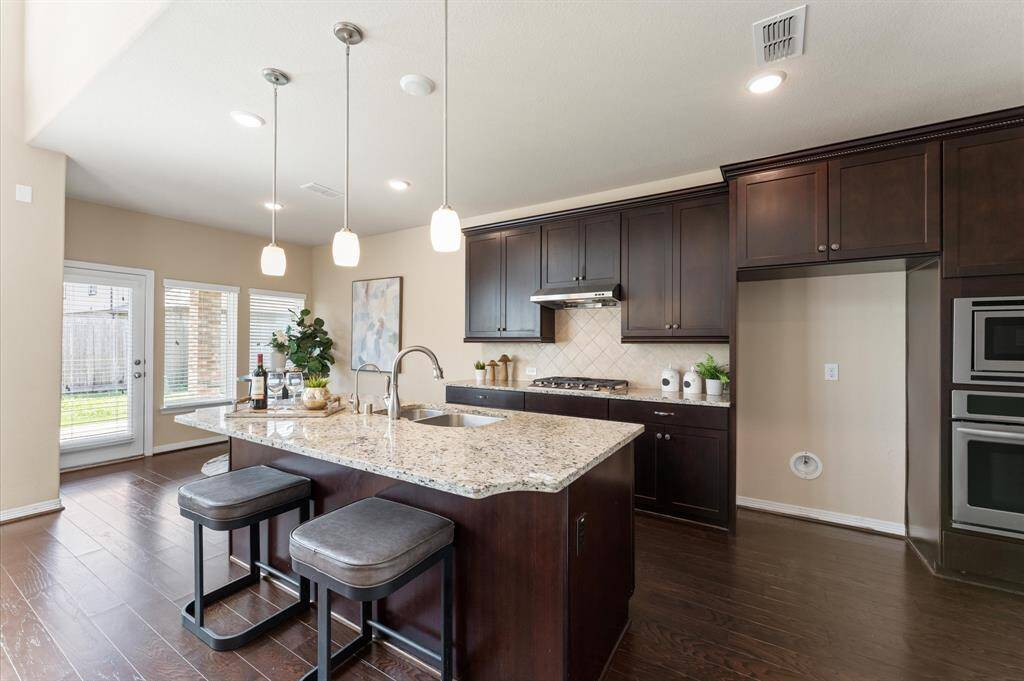 The chef’s kitchen is a dream, with a wide granite island, gleaming sink, and elegant pendant lighting.