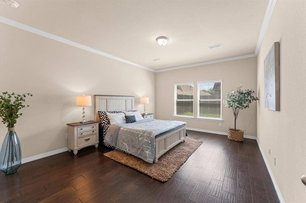 The spacious primary suite is a restful sanctuary with rich wood flooring and wide windows.