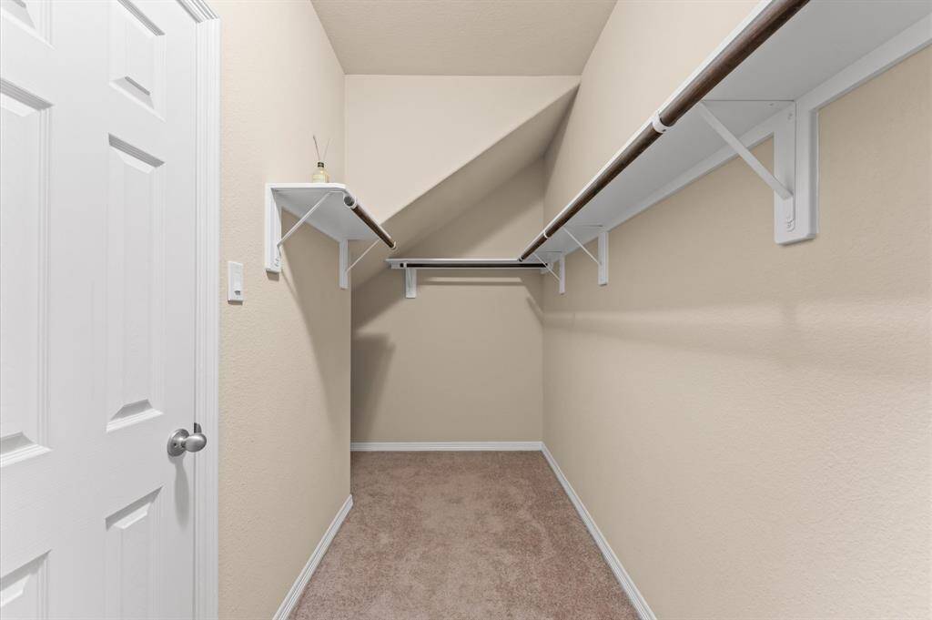 A large walk-in closet with hanging rods keeps everything organized and within reach.