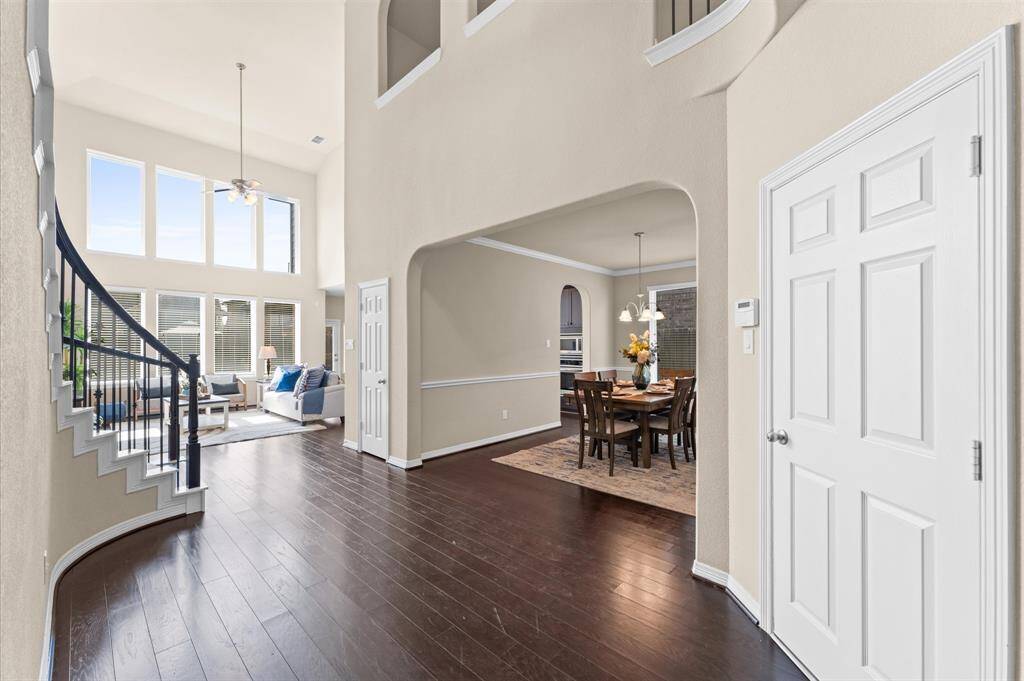 Just beyond, your eyes are drawn to the open living area, with soaring ceilings and bright windows that invite you in.