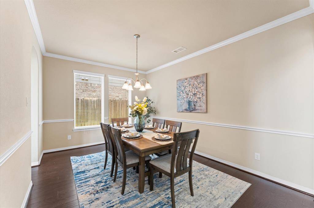 The formal dining room sparkles with a graceful chandelier and sunlight streaming through wide windows.