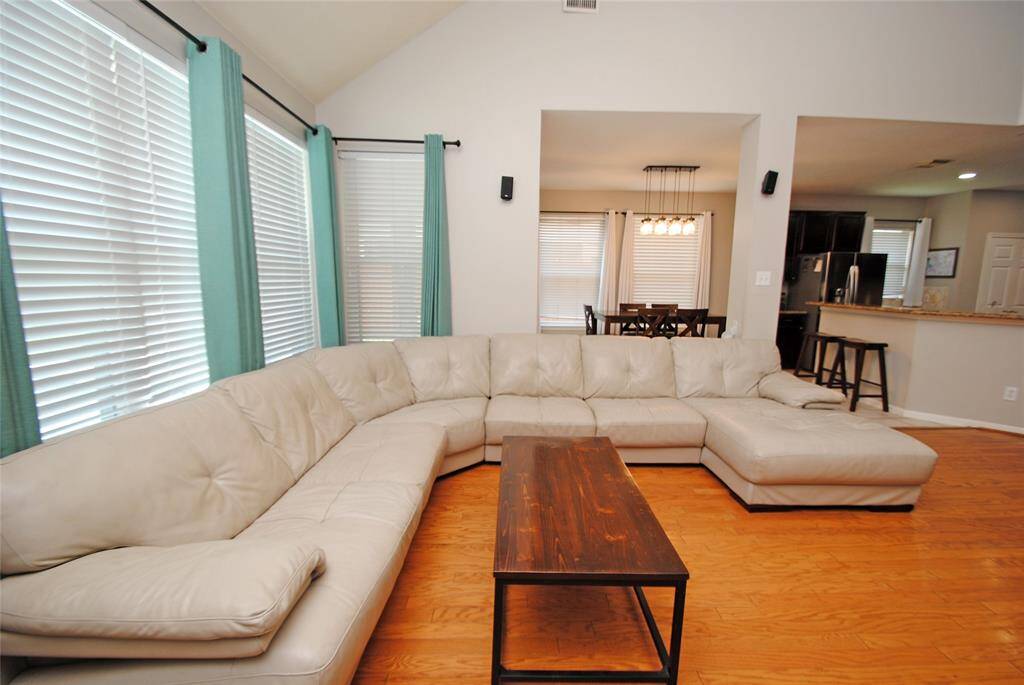 This spacious kitchen features granite countertops, dark wood cabinetry, and stainless steel appliances. An island provides additional workspace, while the open layout connects to a dining area and living room with large windows for natural light.