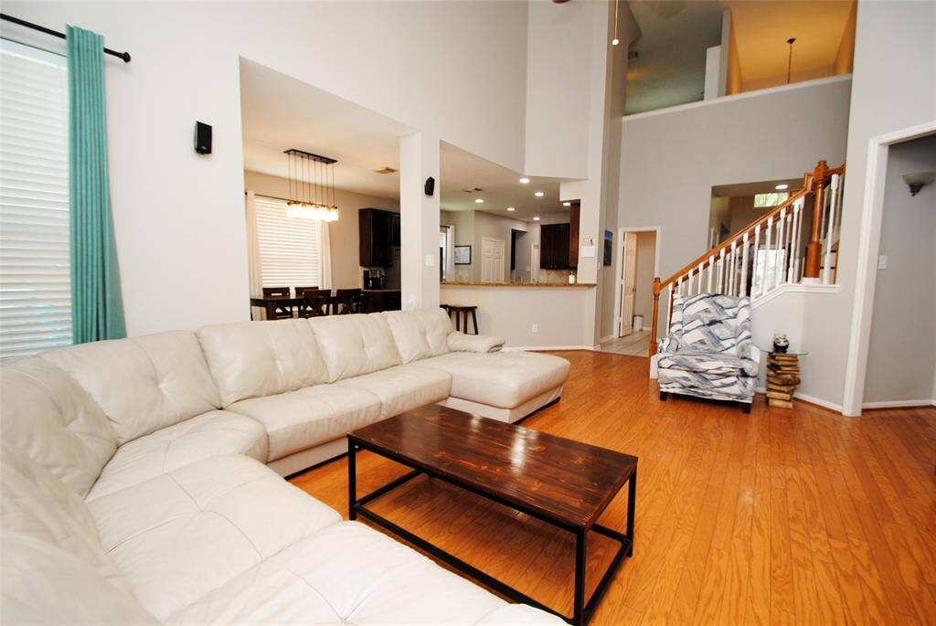 This photo showcases a bright dining area with large windows, offering ample natural light and modern pendant lighting. The space is tiled, and an adjacent open shelf provides storage. A door leads to an outdoor area.