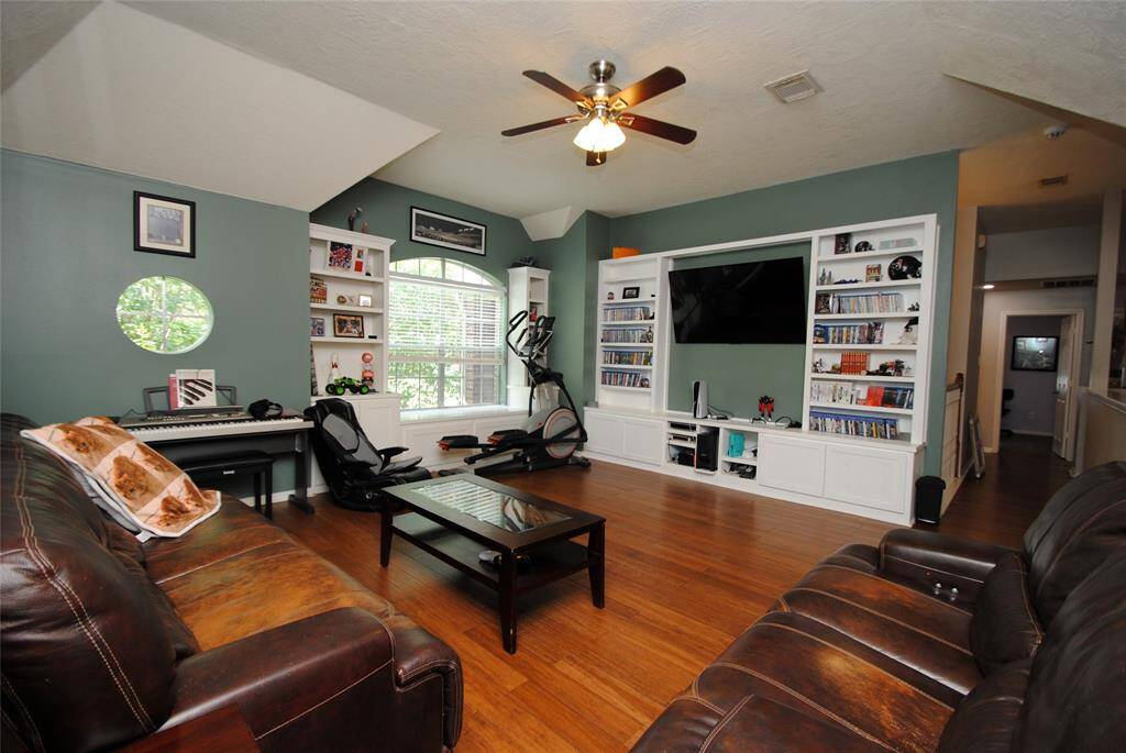 This inviting home features an open living area with high ceilings, a cozy fireplace, and abundant natural light. The hardwood floors and neutral walls provide a warm ambiance. The adjacent dining area is visible, offering easy access for entertaining.