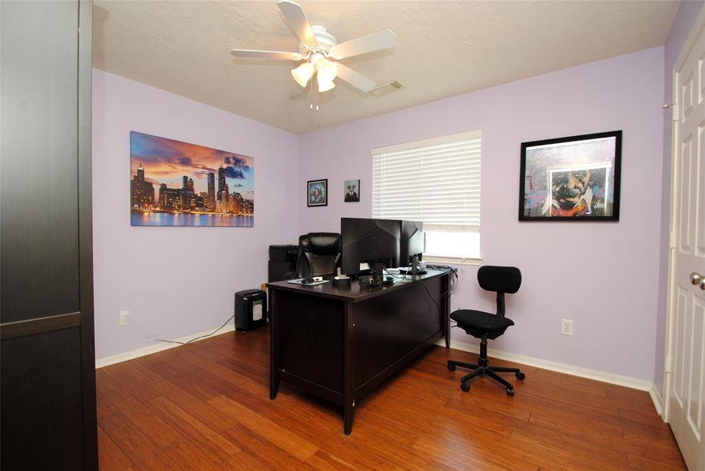 This bedroom features warm wood flooring, soft two-tone walls, and a ceiling fan.
