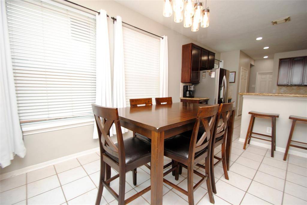 This modern kitchen features dark wood cabinetry, granite countertops, and stainless steel appliances, including a built-in microwave. The open layout connects to a dining area with natural light, creating a welcoming space for cooking and entertaining.