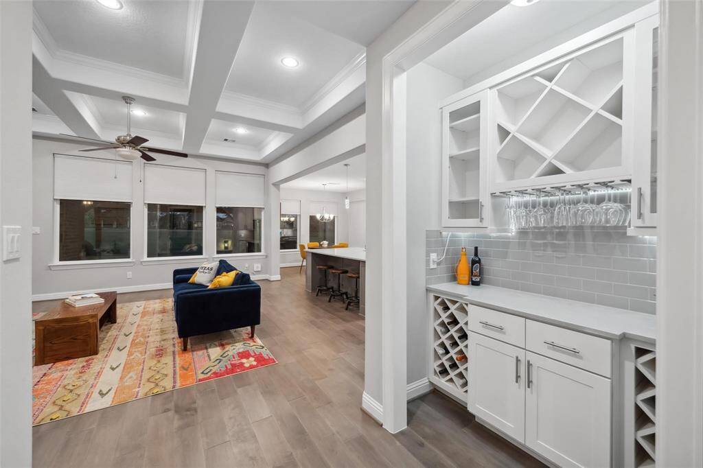 As you transition from the dining area to the living room, you’re greeted by an elegant dry bar featuring a built-in wine rack, classic subway tile backsplash, and stylish cabinetry for all your storage needs.