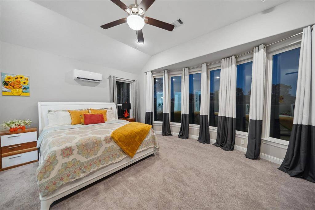 The primary suite offers spacious comfort with soaring ceilings and floor-to-ceiling bay windows that flood the room with natural light, creating a serene and elegant atmosphere.