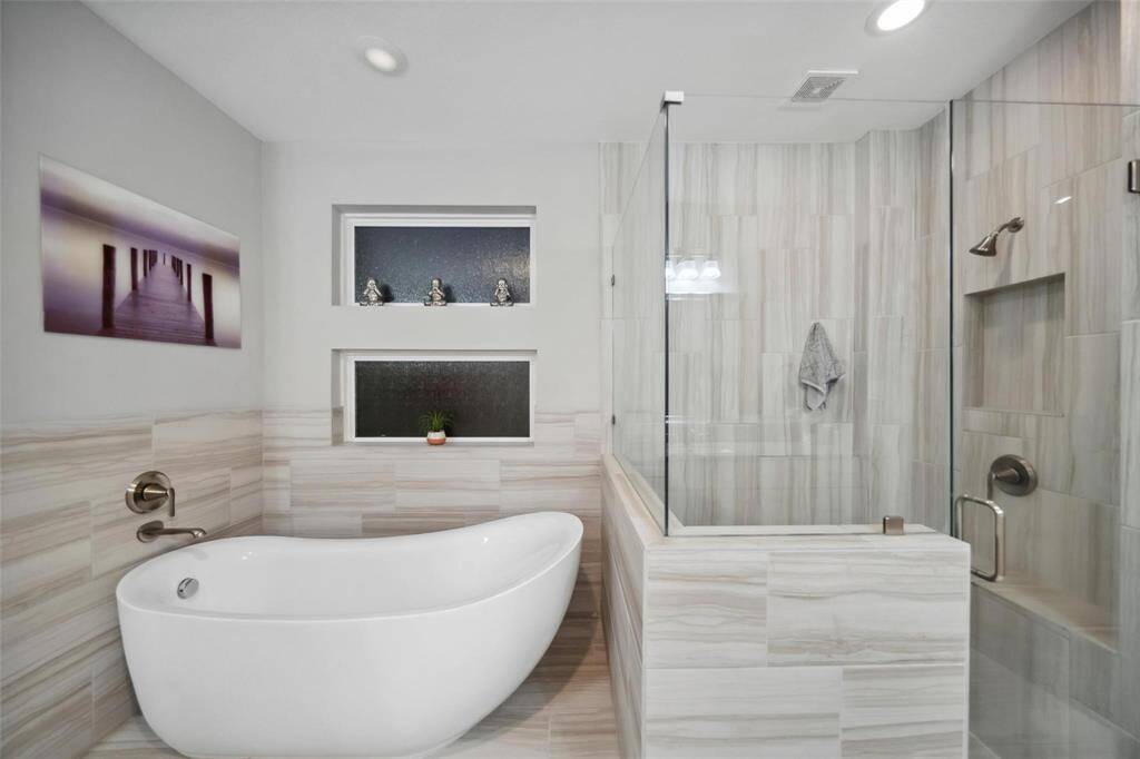 The primary bathroom boasts a modern soaking tub, a spacious shower, and textured windows that provide privacy while bathing the space in soft, natural light—perfect for unwinding after a long day.