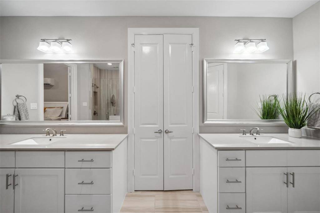 Elegant French doors separate the dual vanities from the large walk-in closet, creating a refined passage to your organized retreat.