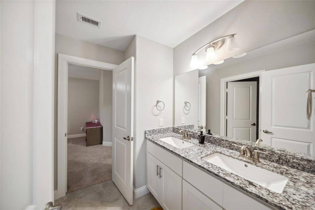 This secondary bathroom connects two bedrooms and offers dual sinks with ample cabinetry—designed for privacy and shared comfort.