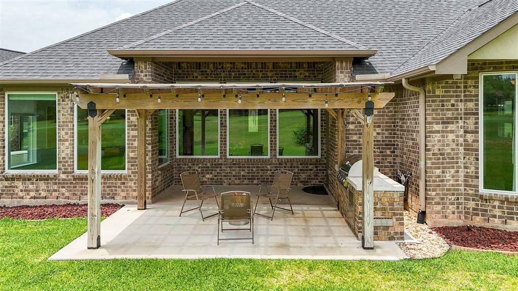 The large covered patio, shaded by a stylish pergola, features a built-in grill—perfect for gatherings, cookouts, and enjoying the outdoors year-round.