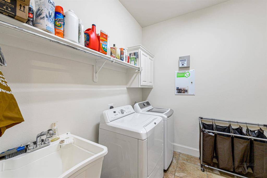 Laundry room complete with sink and shelving for storage.