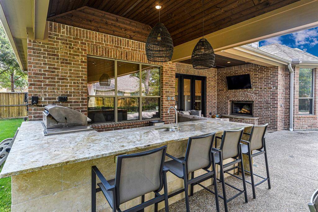 Outdoor kitchen with huge seating bar. Imagine yourself having a meal out here or hosting friends.  You can also see a glimpse of the large side yard with plenty of green space.