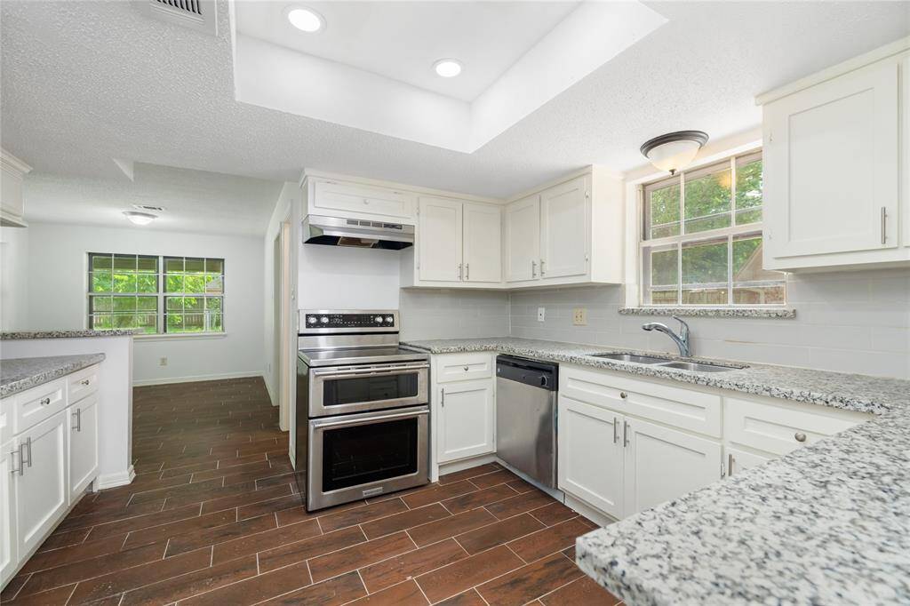 The kitchen shines with stark white cabinetry, elegant marble countertops, a brand new electric oven, and recessed lighting—offering a clean, modern space that’s both functional and beautiful.
