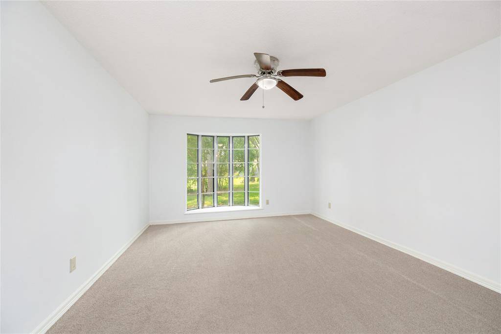 The spacious primary suite offers a quiet retreat with a bay window, soft natural light, and a ceiling fan for year-round comfort.