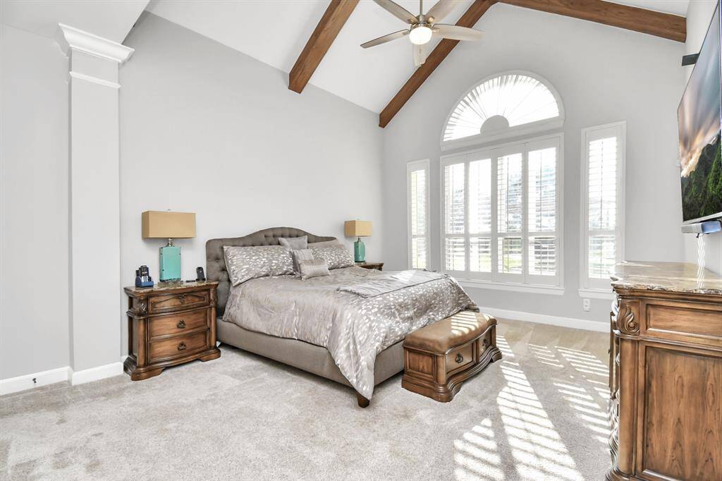This master bedroom is a serene and sophisticated retreat, distinguished by its expansive space and dramatic vaulted ceiling, that adds a sense of grandeur and openness. The high, angled ceiling often showcases exposed beams or detailed architectural moldings that contribute to the room’s luxurious feel. The vertical space enhances the room's airy and expansive atmosphere, making it feel both grand and inviting.