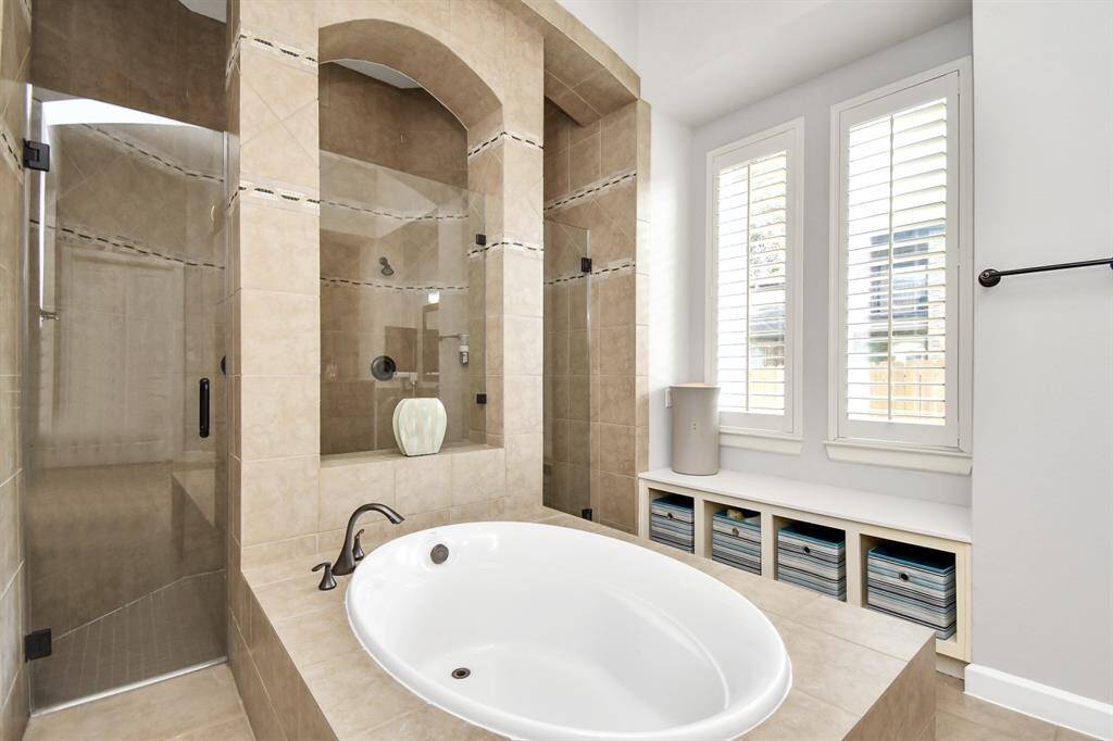 The master bathroom features a large, walk-in shower that serves as a focal point of the space. The shower area is enclosed with frameless glass doors, offering an unobstructed view and a sense of openness and the grand bathtub is a luxurious retreat designed for both relaxation and functionality. Its thoughtful design, high-end fixtures, and elegant finishes create a serene and indulgent environment, making it a perfect sanctuary for unwinding and rejuvenation.