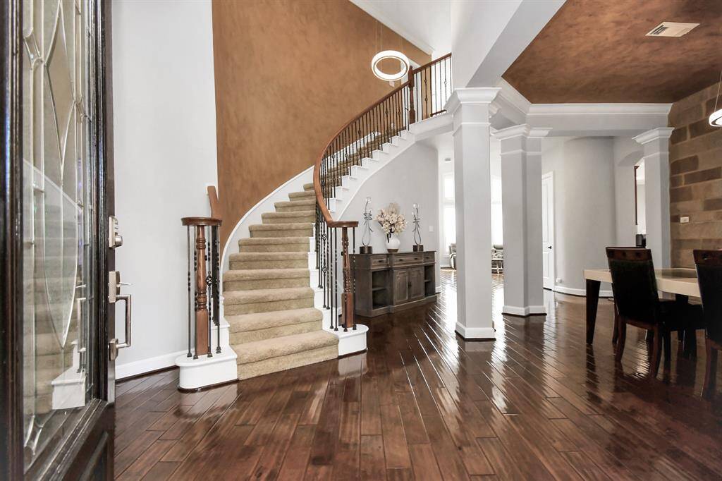 Upon entering, your attention is immediately drawn to the magnificent staircase that is the centerpiece of the foyer. The staircase, a true architectural marvel, gracefully ascends in a sweeping curve, its polished wooden treads reflecting the soft light from the grand chandelier above.