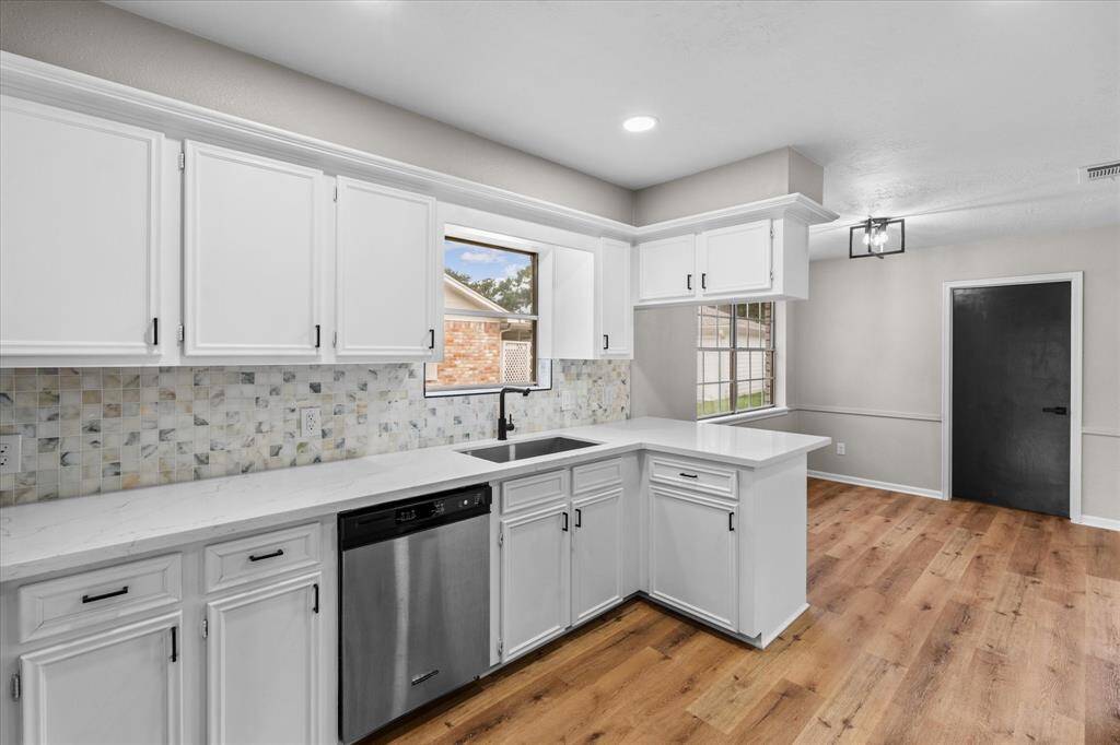 View of the kitchen sink and dishwasher with beautiful backsplash