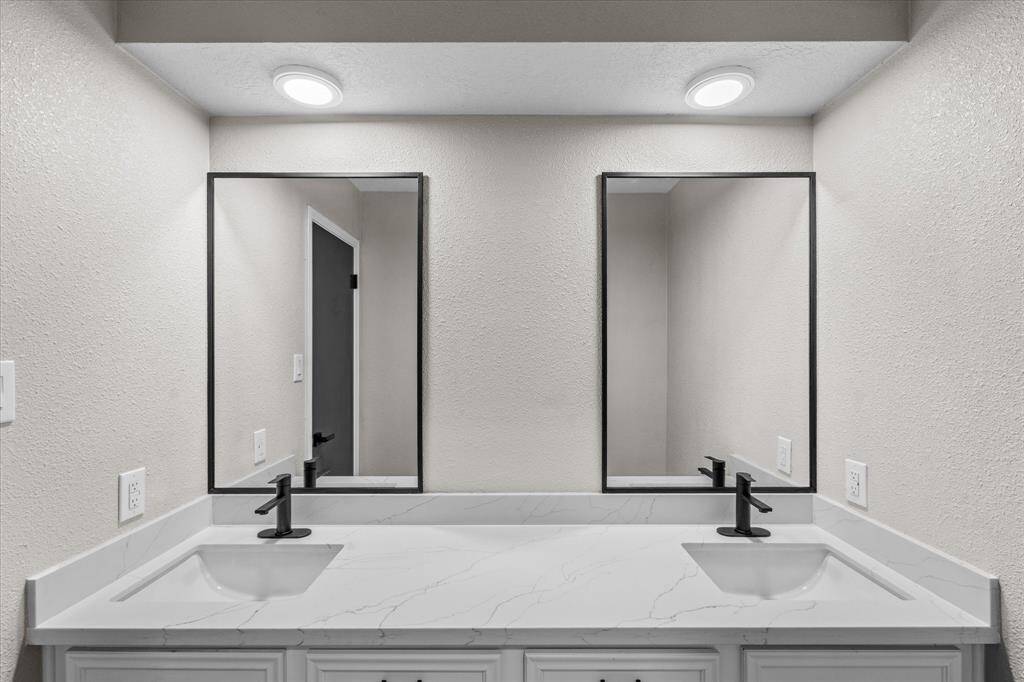 Beautiful custom made mirrors and double vanity sinks in the guest bath separating the tub/shower combo and toilet area