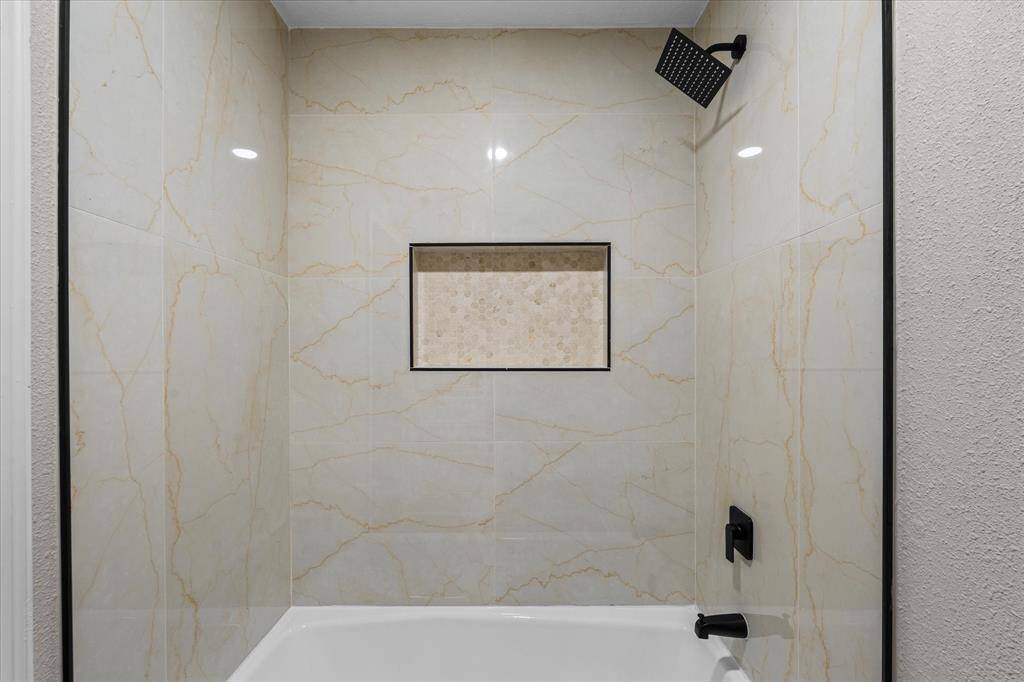 Secondary/Guest tub and shower combo. New porcelain tile with niche and wide shower head