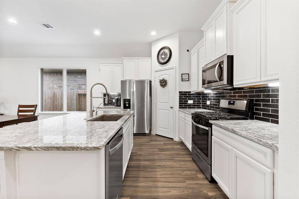 Premium granite slab, large sink and upgraded faucet with a beautiful black backsplash