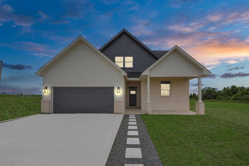 A modern, two-story home with a spacious driveway and a two-car garage. The exterior features a mix of light siding and dark accents, complemented by a neatly landscaped front path. Offering a serene and inviting atmosphere.