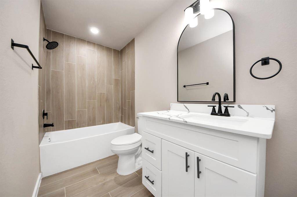 A modern, two-story home with a spacious driveway and a two-car garage. The exterior features a mix of light siding and dark accents, complemented by a neatly landscaped front path. Offering a serene and inviting atmosphere.