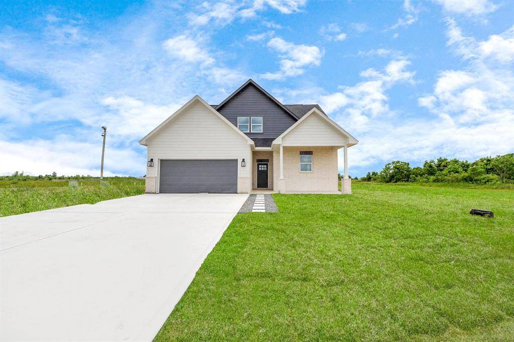 A modern, two-story home with a spacious driveway and a two-car garage. The exterior features a mix of light siding and dark accents, complemented by a neatly landscaped front path. Offering a serene and inviting atmosphere.