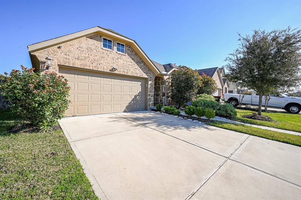 Charming single-story brick home with a two-car garage, a well-maintained lawn, and tidy landscaping. The driveway is spacious, and the exterior features a combination of brick and stone accents.