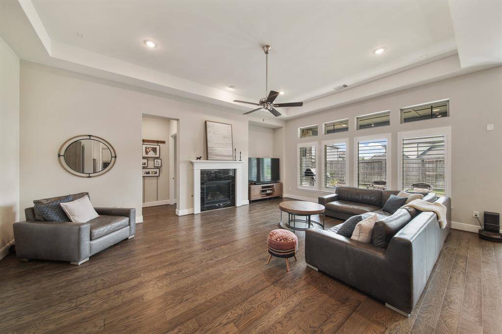 The living area is both grand and inviting, featuring a beautifully trayed ceiling that adds architectural interest, a striking center fireplace as a focal point, and an open layout ideal for both relaxing and entertaining.
