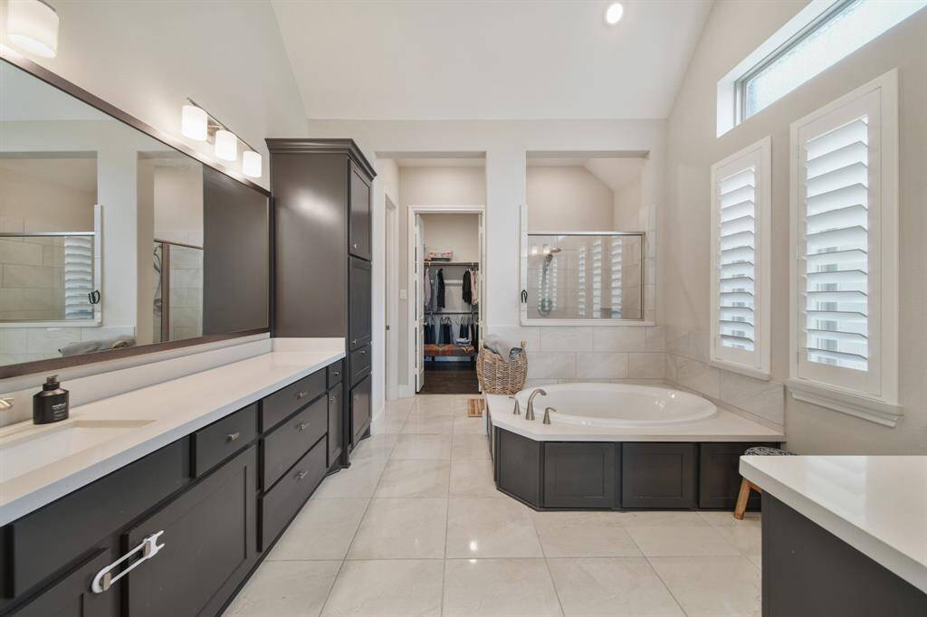 The primary bath features dual vanities, providing ample personal space along with an abundance of custom cabinetry for seamless organization.