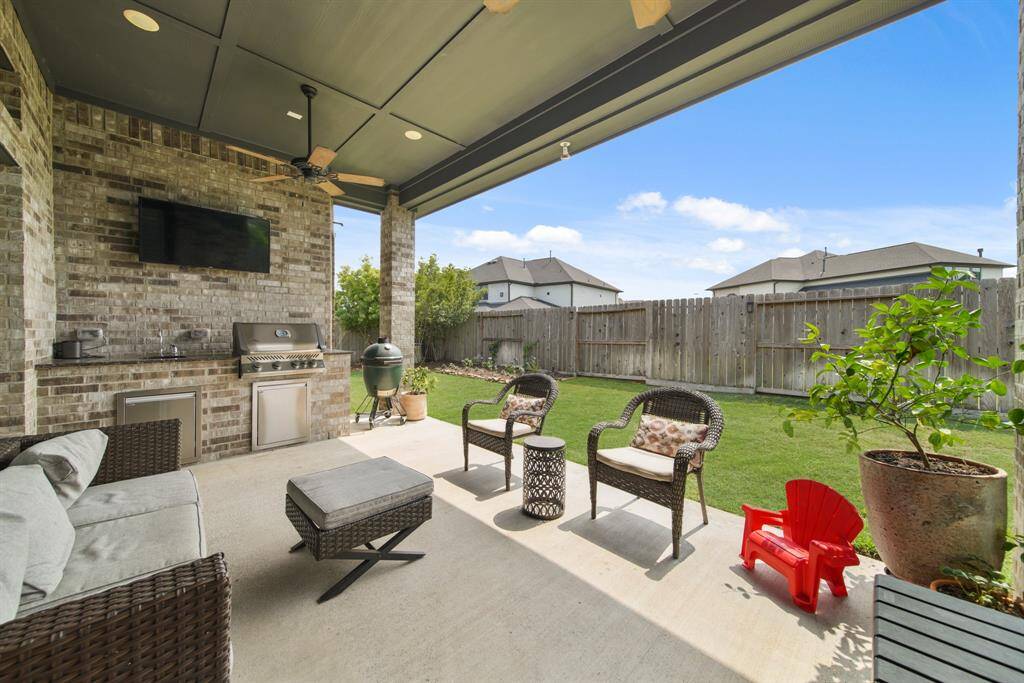 Step outside to the covered patio, where a fully equipped outdoor kitchen awaits—perfectly designed for alfresco dining and seamless entertaining in any season.