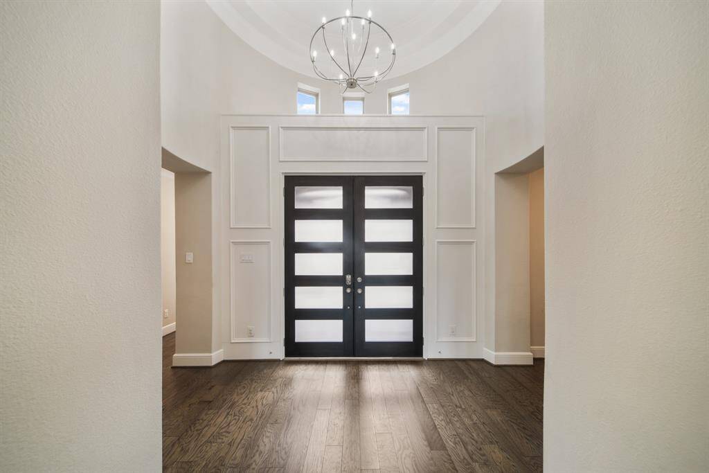 A soaring trayed ceiling crowned by a breathtaking chandelier creates a dramatic focal point, adding a touch of grandeur and artistry to the space.