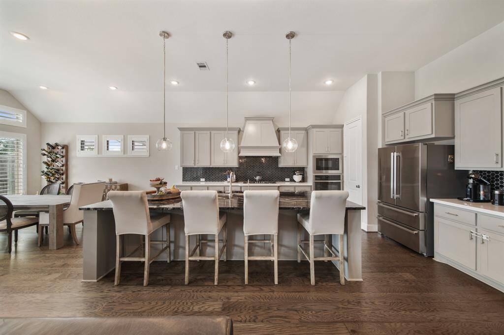 Your chef inspired kitchen awaits! Features include granite countertops paired with a coordinating tile backsplash, stainless steel appliances, rich cabinets with updated hardware, recessed lighting, pendant lighting and a sprawling island with breakfast bar seating.