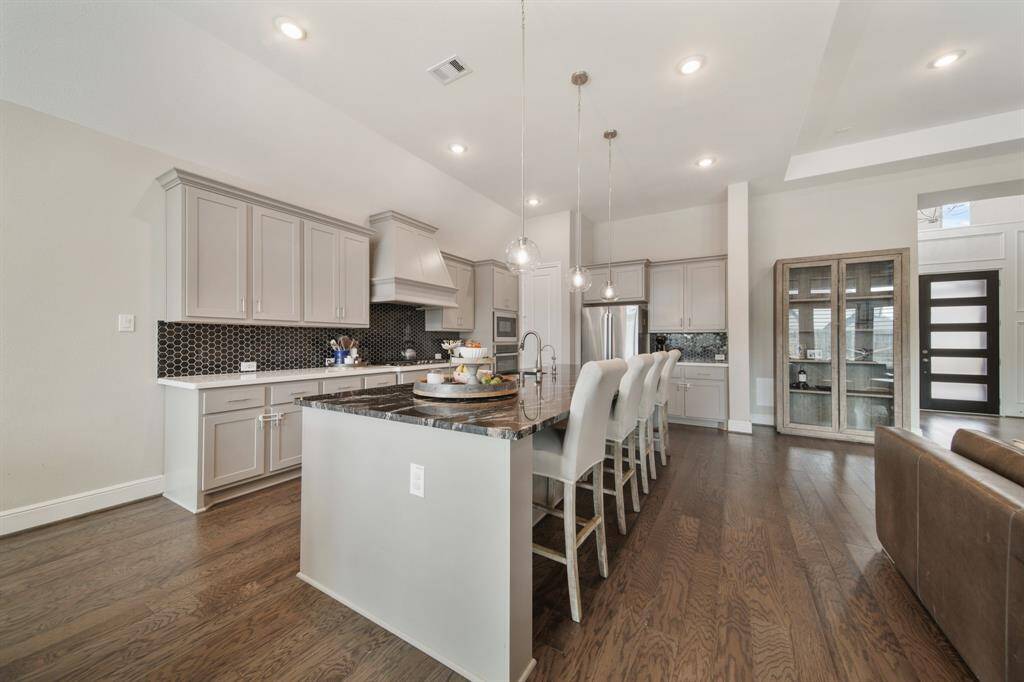 The sprawling island with breakfast bar seating serves as a versatile centerpiece, providing additional workspace, storage, and seating for casual dining or entertaining.