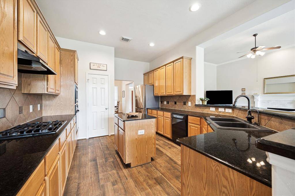 This immaculate kitchen is the perfect place to show off your culinary skills, featuring gorgeous granite countertops, tile backsplash, sleek black appliances, abundant cabinetry, a spacious walk-in pantry, and more.
