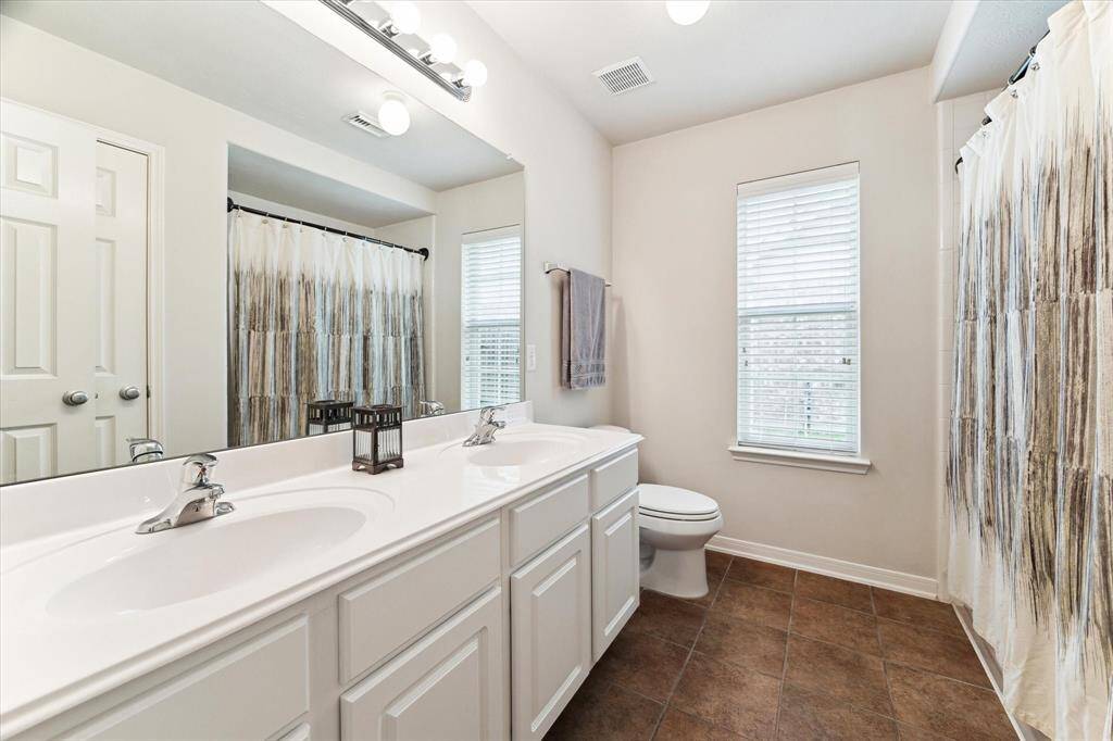 This is one of three full bathrooms making the morning rush a snap. This guest bathroom offers a dual sink vanity with a full mirror and vanity lights above plus a convenient tub/shower enclosure.