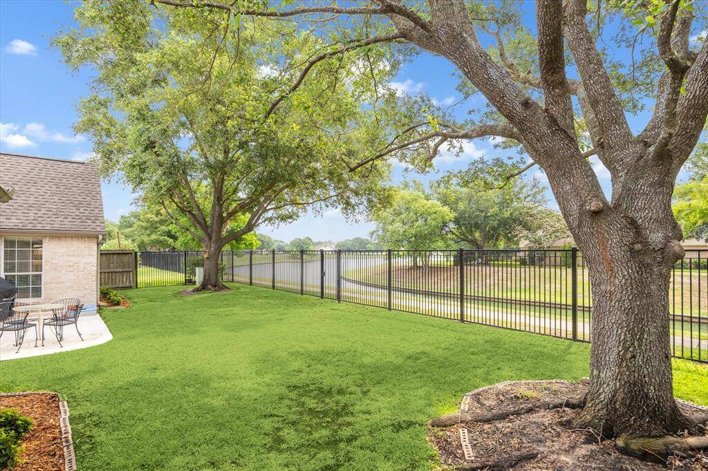 Take in peaceful views of the lake and surrounding greenery from your own backyard, where an iron fence offers direct access to the scenic trails and lake just behind the property.