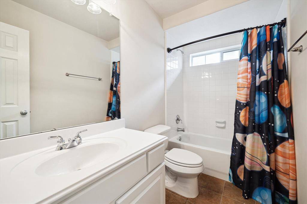 This spotless guest bathroom offers a single sink vanity plus a fully tiled tub/shower enclosure.