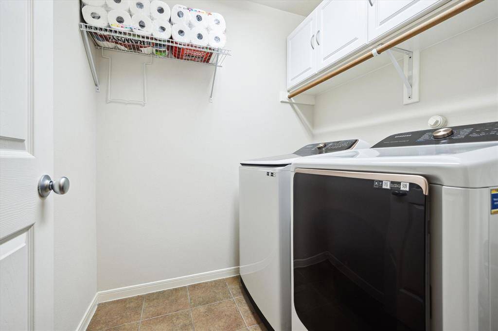 Laundry day is a breeze in this spacious utility room, complete with a convenient hanging bar for clothes, built-in shelving and cabinetry for storage, washer hookups, and electric dryer connections.